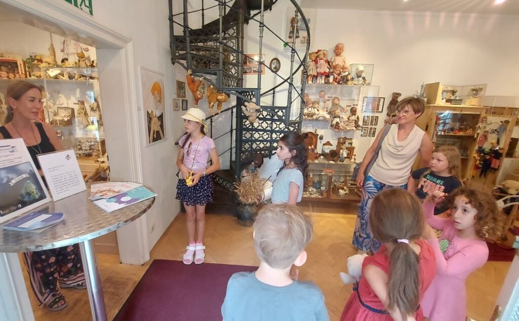 Kinder im Sommergewand tummeln sich im Puppen- und Spielzeugmuseum
